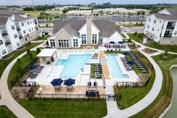 A large swimming pool surrounded by a grassy area and a building in the background.